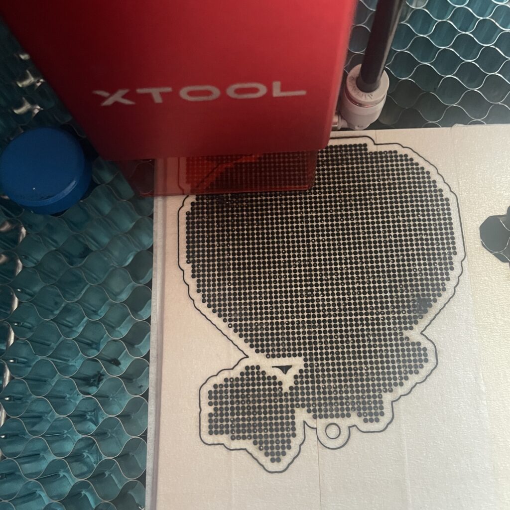 wooden cross-stitch template of a pumpkin being cut on a Xtool laser machine