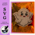 A white, friendly ghost cross-stitch home decoration. Cut out of 3mm plywood with a cross-stitch design embroidered on, and resting on Autumn coloured leaves.