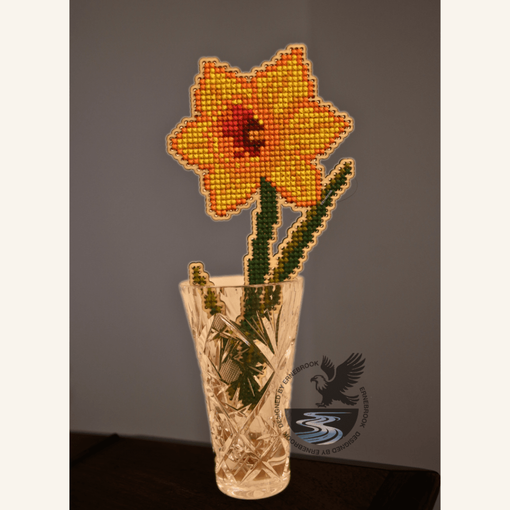 Image of a yellow daffodil template in wood and completed with cross stitch embroidery in a small glass vase.