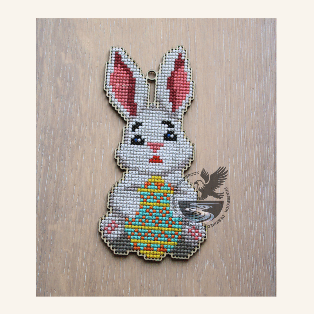 Image of a wooden template of an Easter bunny holding a decorative egg and completed with cross stitch embroidery
