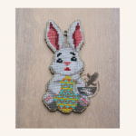 Image of a wooden template of an Easter bunny holding a decorative egg and completed with cross stitch embroidery