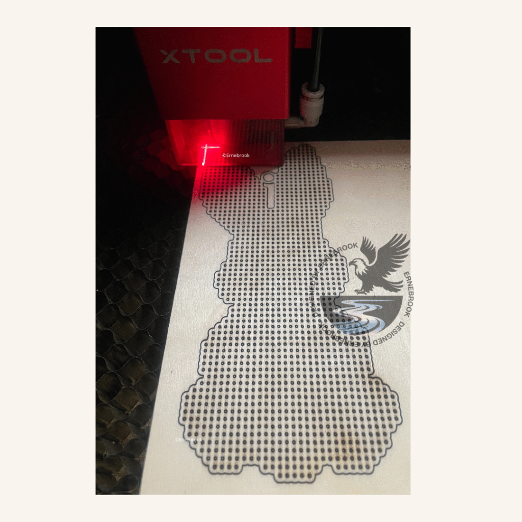 A wooden cross stitch template of an easter bunny being cut on a laser machine