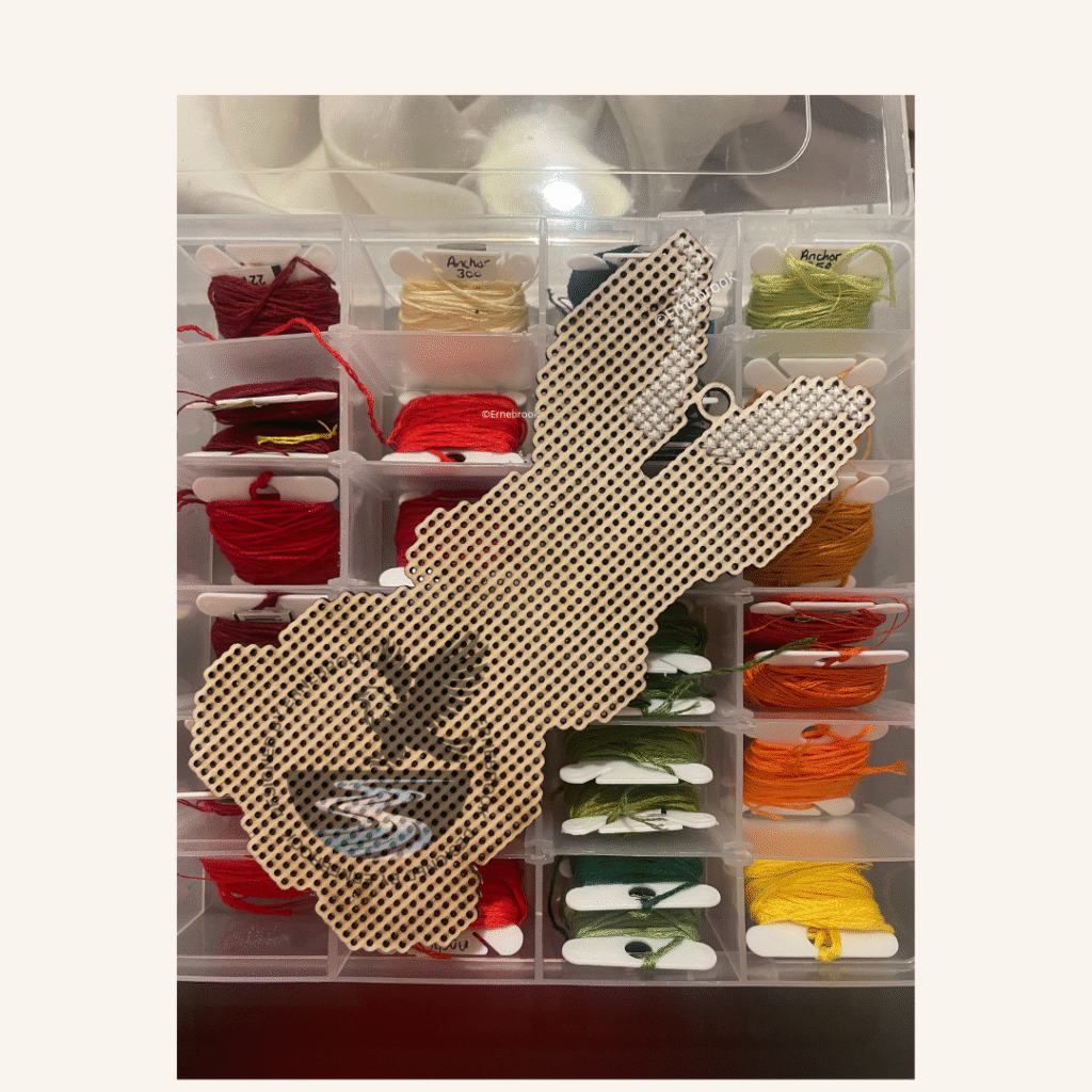 An uncompleted cross-stitch project of an Easter bunny with a selection of embroidery threads.